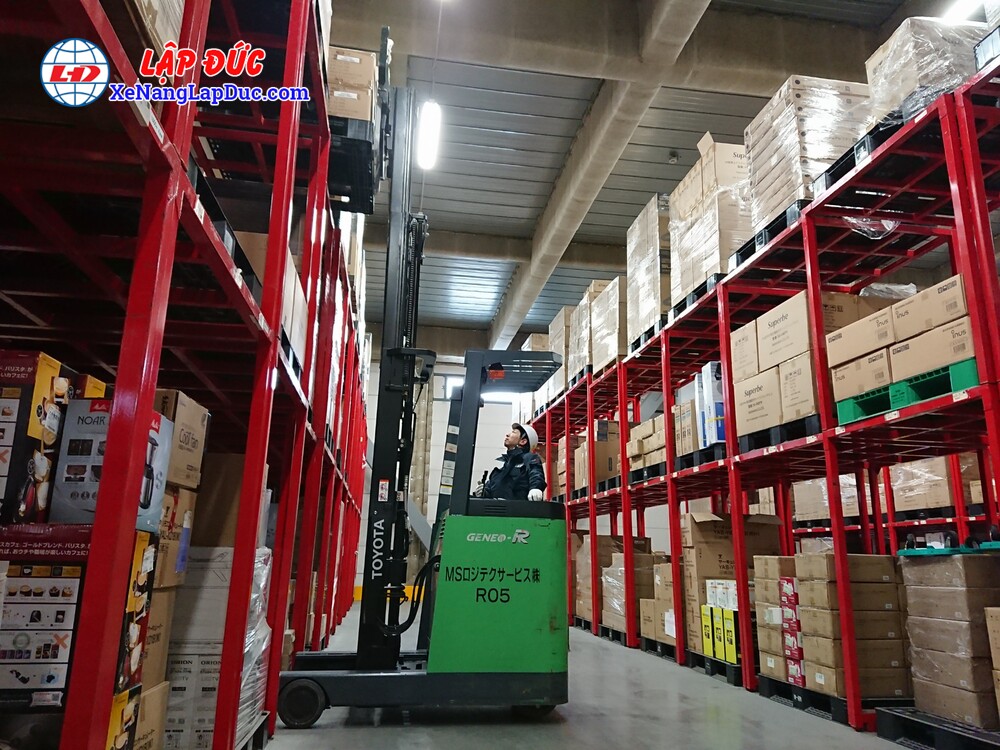 Xe nâng điện đứng lái đang làm việc trong kho hàng Xe nâng điện đứng lái đang làm việc trong kho hàng